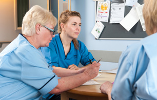 Three nurses sitting round a desk talking