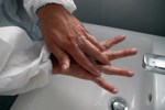 Person wearing scrubs washing hands