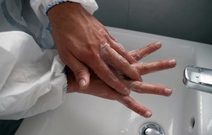Person wearing scrubs washing hands