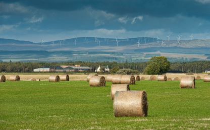 A view of rural Scotland with hay bales and hills in the distance