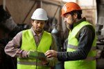 Two facilities management staff members wearing high visibility waistcoats and hard hats.