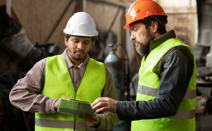 Two facilities management staff members wearing high visibility waistcoats and hard hats.