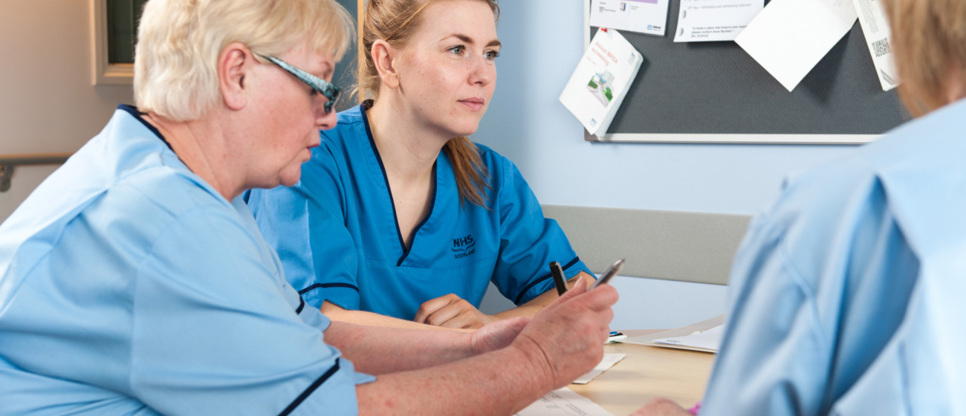 Three nurses sitting round a desk talking